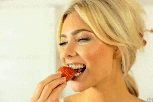 Анимированная открытка Девушка, подмигивая, ест клубничку.